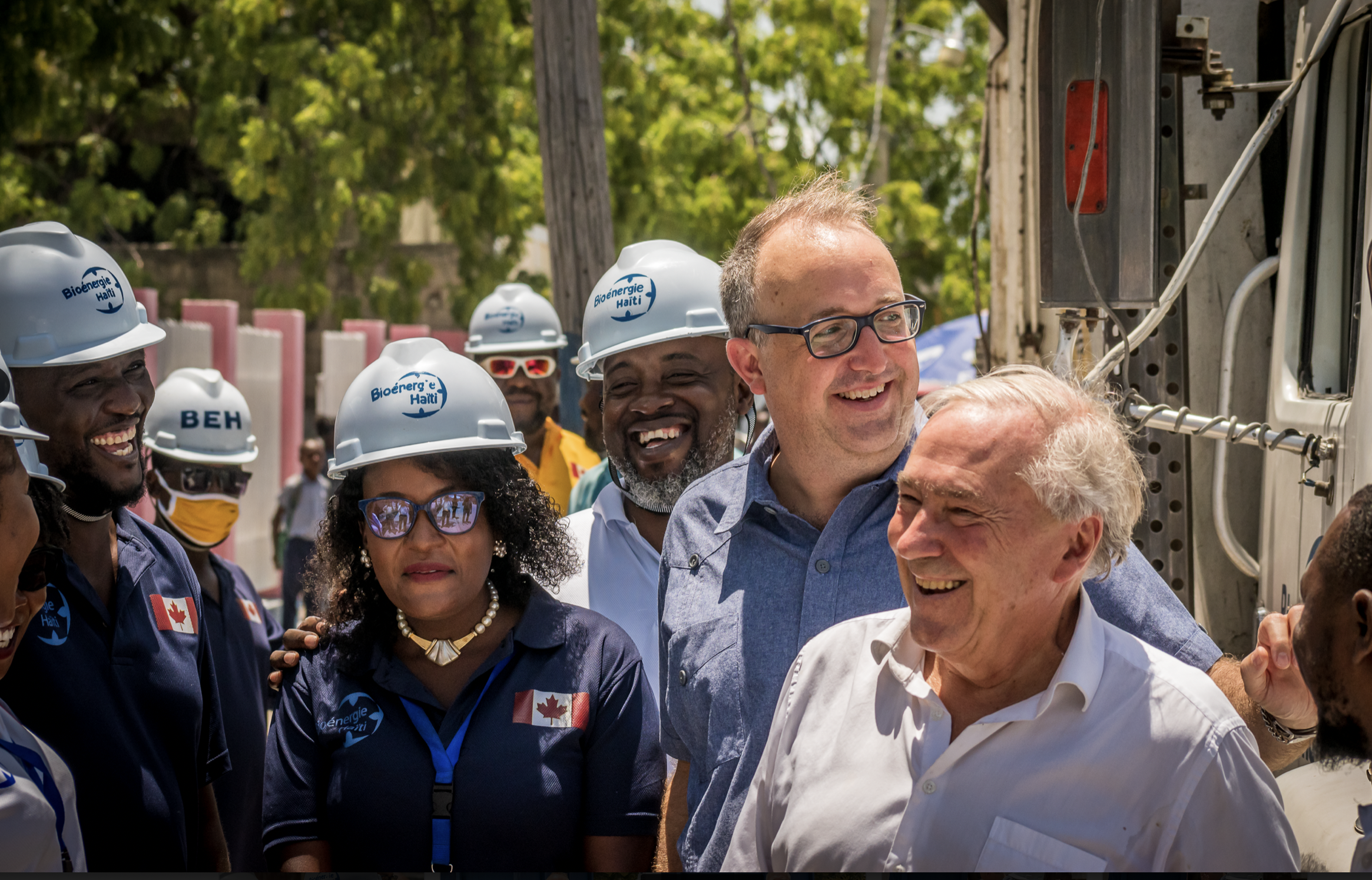 Personnes souriantes dehors, certaines ayant un casque Bioénergie Haïti